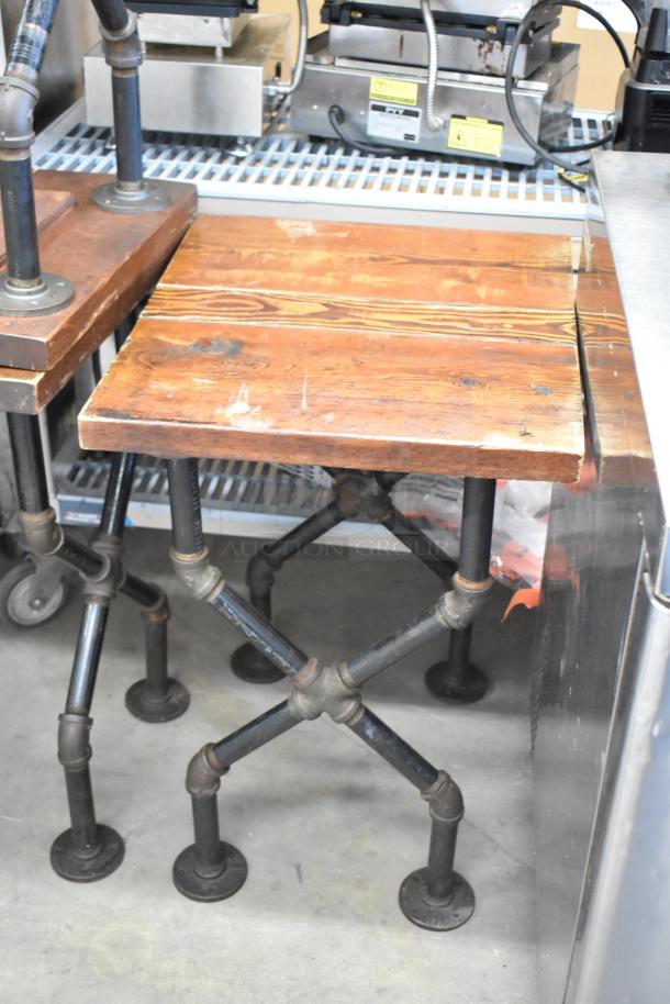 Eight tables with wooden tabletops and industrial pipe legs, showing minor wear. Auction lot includes all items.