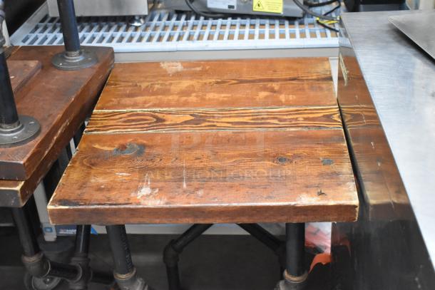 8 tables with wooden tabletops, rustic finish, visible wear. Sturdy metal legs, suitable for industrial decor.