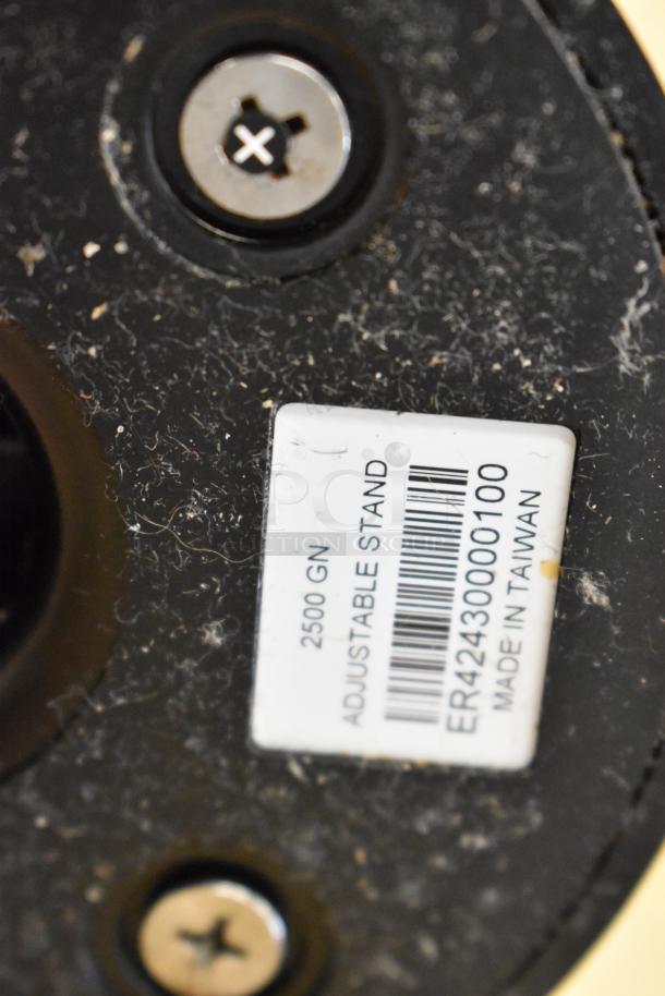 Close-up of a label on a black adjustable stand. Text reads: "2500 GN, ADJUSTABLE STAND, ER4243000100, MADE IN TAIWAN." Dust present.