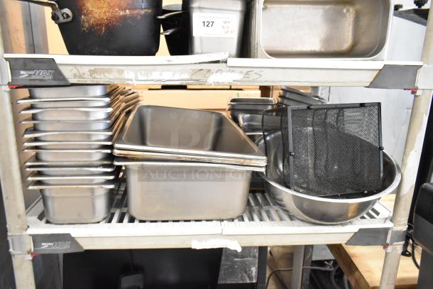 Lot of assorted kitchen items on shelves, including stainless steel stock pots, drop-in bins, and bowls. Used condition.