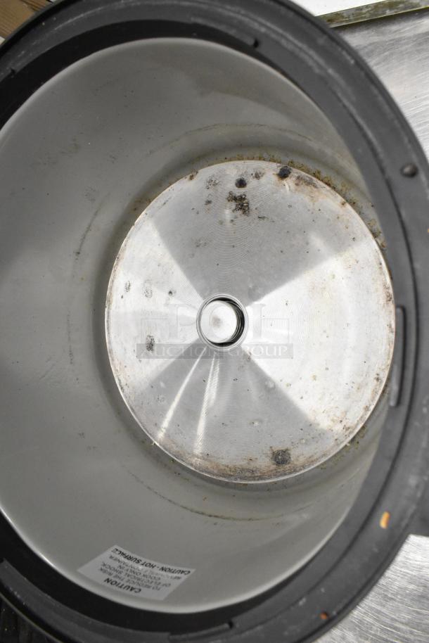 Aroma ARC-1130S stainless steel rice cooker interior showing signs of wear; caution label partially visible.