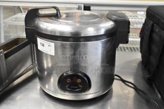 Amko AK-60ERC stainless steel countertop rice cooker, model AK-60ERC, 120 volts, shown with handles and auction tag.