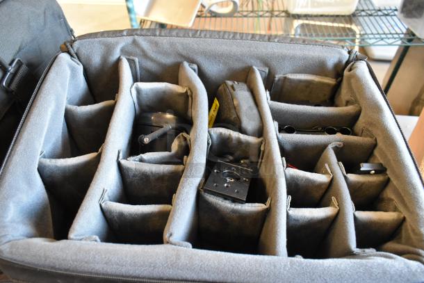 Four black bags with organized compartments, possibly containing electronic accessories, padded for protection.