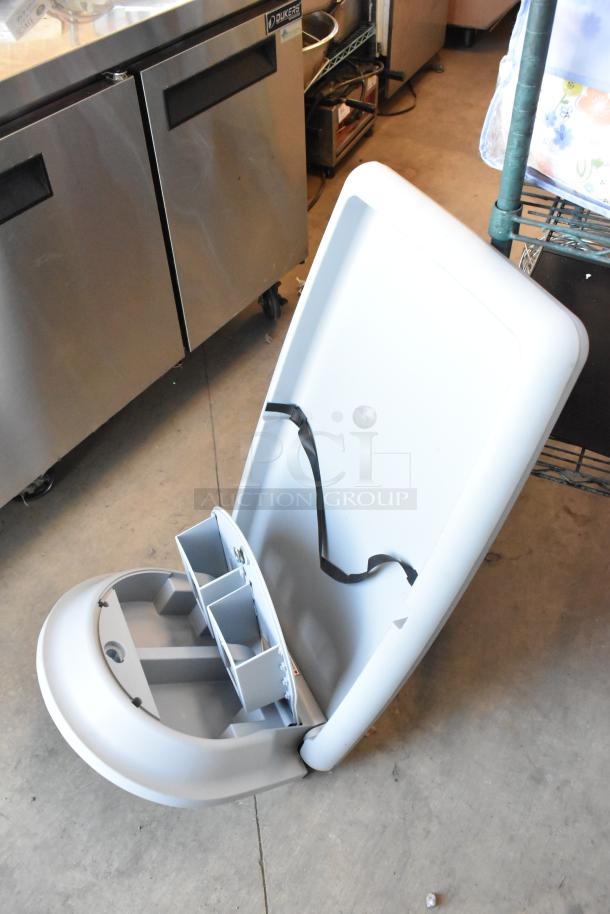 Koala Kare gray wall mount diaper changing station, features safety straps, open condition, suitable for commercial use.