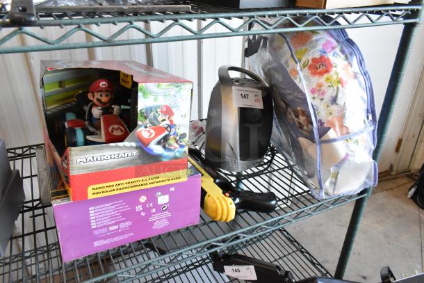 Lot of items including Mario Kart RC toy in box, heater with label "147", GiveBest PTC-905 salt gun, and Boppy pillow in floral bag.