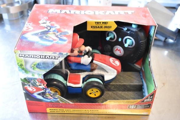 Mario Kart remote controlled toy in original packaging, featuring Mario figure in kart with controller. Packaging has minor wear.