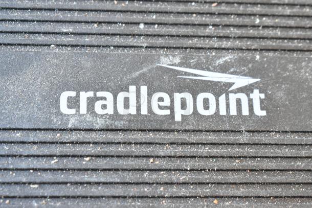 Cradlepoint AER2200 router with dust on the surface; logo visible. Part of a lot including Star TSP100 printer, Verizon phone.