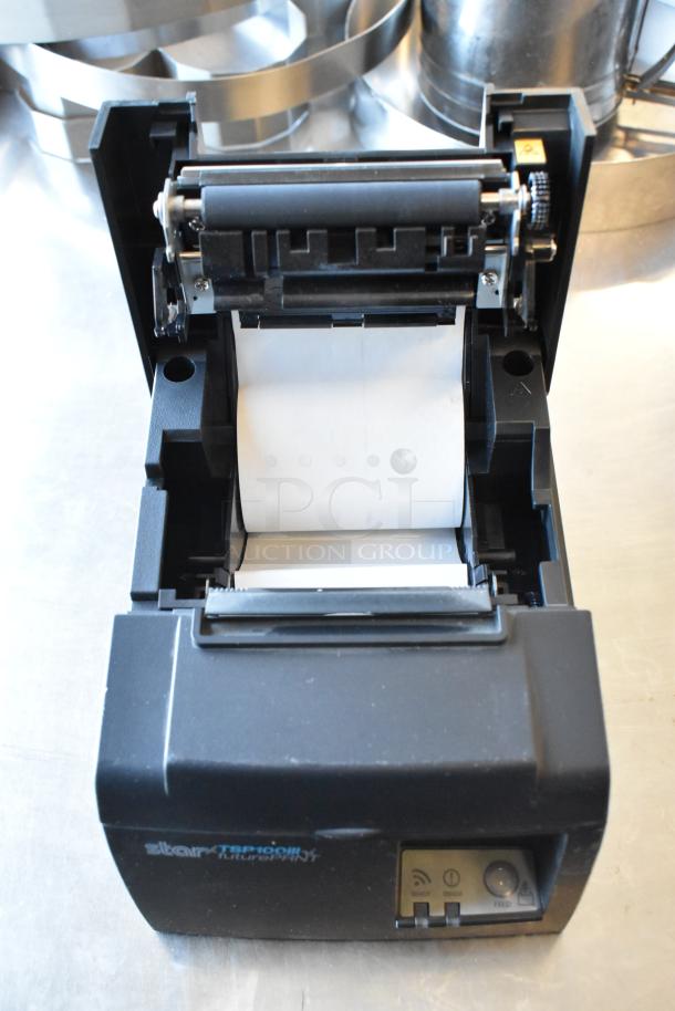 Star TSP100 receipt printer with open paper compartment, showing internal rollers and partial paper roll.