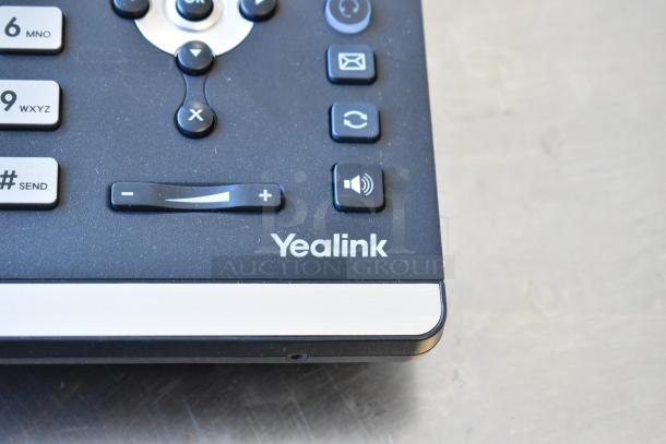 Close-up of a Yealink corded telephone keypad with buttons for volume control and various functions.
