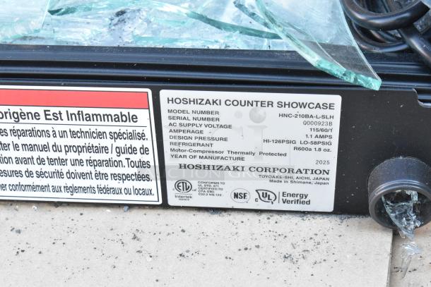Hoshizaki HNC-210BA-L-SLH sushi display with broken glass. Label shows model, serial number Q000923B, and voltage details.