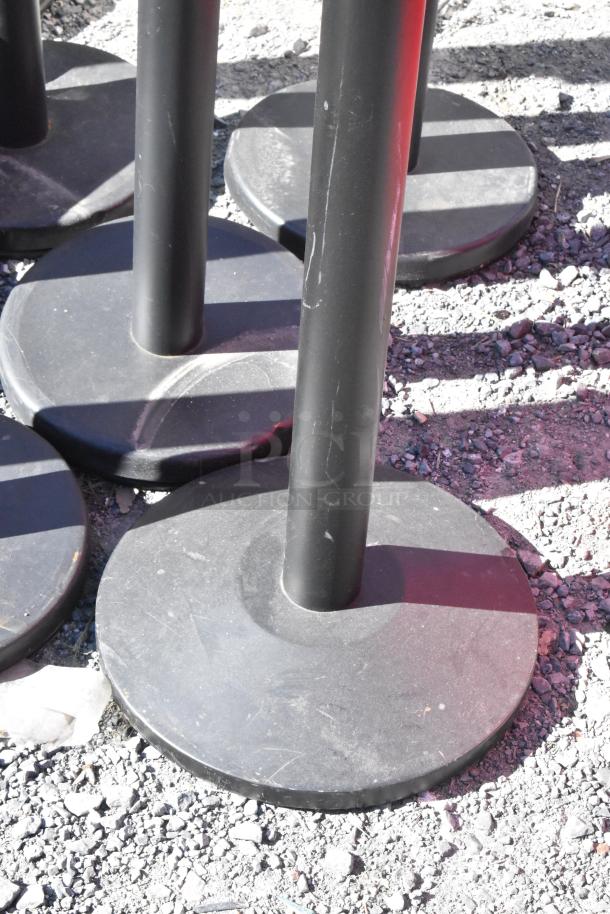 10 black QueueWay stanchions with round bases, outdoor, used condition, suitable for crowd control or event organization.