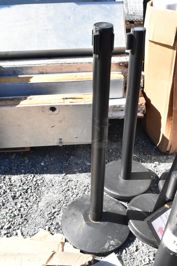 10 QueueWay black stanchions with round bases, used condition, ideal for crowd control.