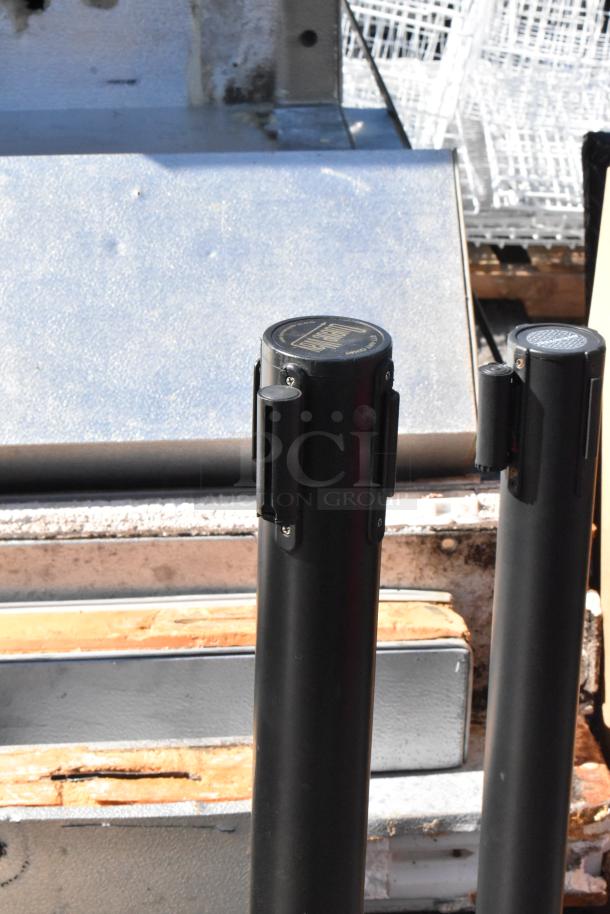 10 QueueWay stanchions, black, durable, slightly worn. Ideal for crowd control. Sold as a set for auction.