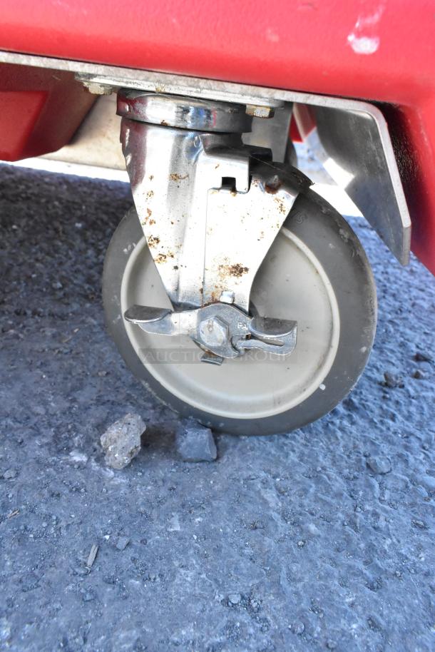 Cambro red poly work station caster in commercial use. Caster shows signs of wear and some rust, attached to red base.