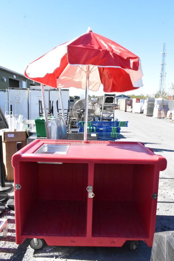 Cambro red poly portable work station with umbrella and commercial casters, featuring dual storage compartments.