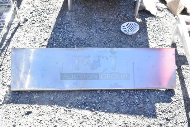 Two wall mount metal shelves, dimensions 48x12x12 inches, in used condition on a gravel surface.