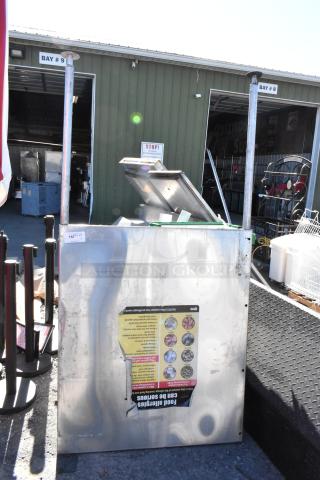 Stainless steel panel with visible wear and attached informational sticker, outdoors, in fair condition, industrial setting.