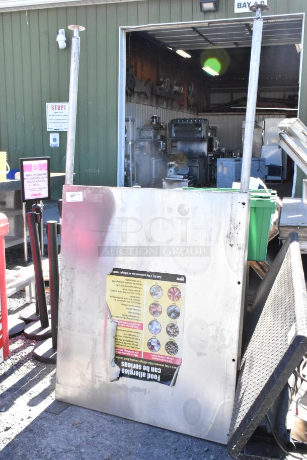 Stainless steel panel with visible wear, measures approximately 4x3 feet. Attached sign with safety graphics and cautions.