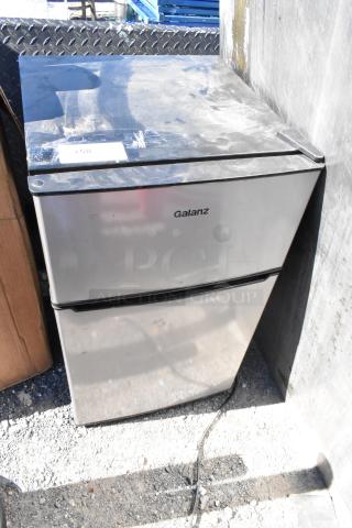 Galanz GLR31TS1E02 mini cooler with freezer, silver finish, visible signage, powered by 115 volts, 1 phase. Some surface wear.