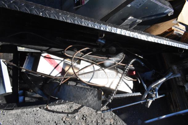 Black diamond plate pickup truck box with various contents; visible cables and components, in fair condition.