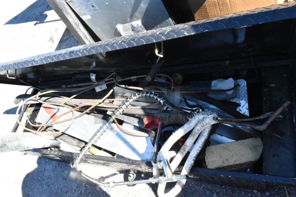 Black diamond plate pick-up truck box with assorted contents, open view. Includes wires and metal rods. Used condition.