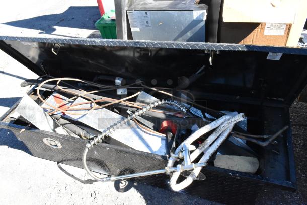 Black diamond plate pickup truck box, open, showing assorted tools and contents inside, in good condition.
