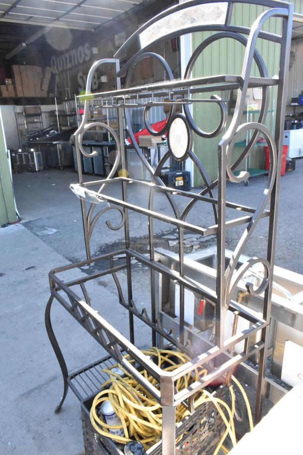 Metal frame with decorative scrollwork holds various contents, including hoses and tools. Moderate wear, industrial setting.