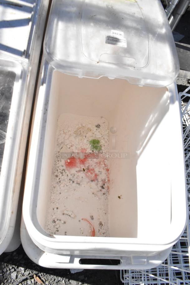 White poly ingredient bin on commercial casters, open lid, showing interior with minor debris and a label on lid. Slight wear visible.
