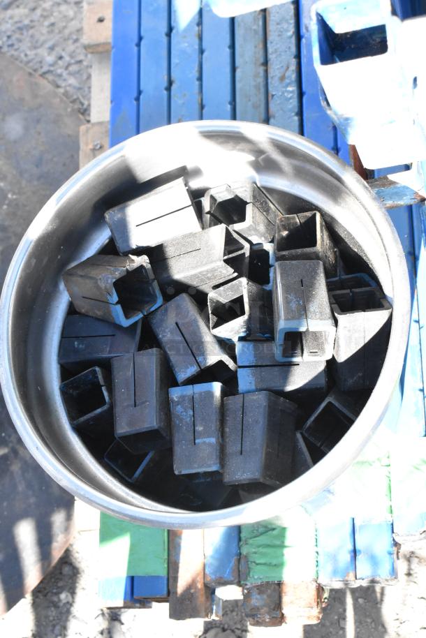 A container filled with rectangular, black metal brackets, possibly related to the blue metal wire shelves and poles mentioned.