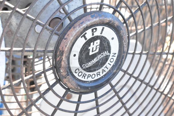 2 TPI FE-75S1fOL floor metal fans, 115V, 1 phase, with TPI logo on grill, visible wear. Auction for two units.