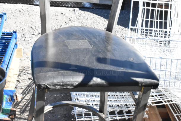 Black metal bar height chair with a padded seat, showing light wear. Comes as part of a set of five assorted chairs.