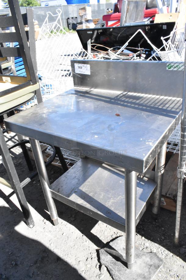 Stainless steel table with under shelf and back splash, used condition, visible sticker shows item number and quantity.