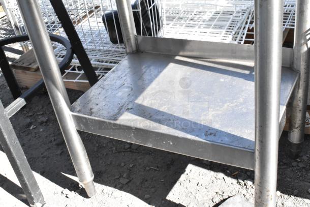 Stainless steel table with under shelf and back splash, showing signs of wear, ideal for kitchen or industrial use.