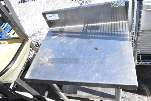Stainless steel table with under shelf and back splash, showing signs of wear. Markings visible on back splash.