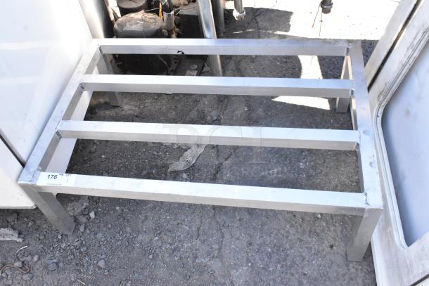 Modern stainless steel dunnage rack, robust design, minor wear. Tag reads "176." Ideal for storage solutions.