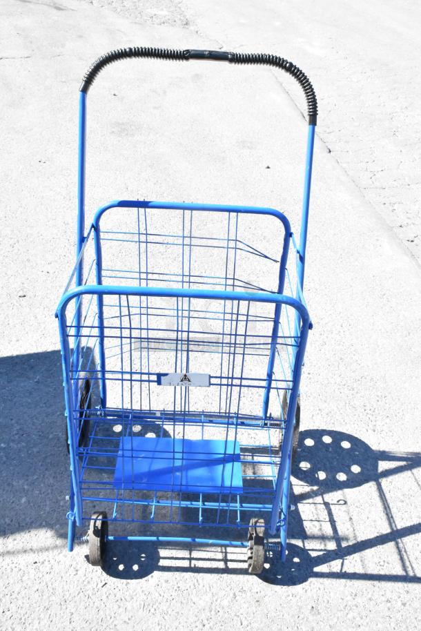 Blue metal basket cart with folding handle, two wheels, and sturdy wireframe construction. Slight wear visible.
