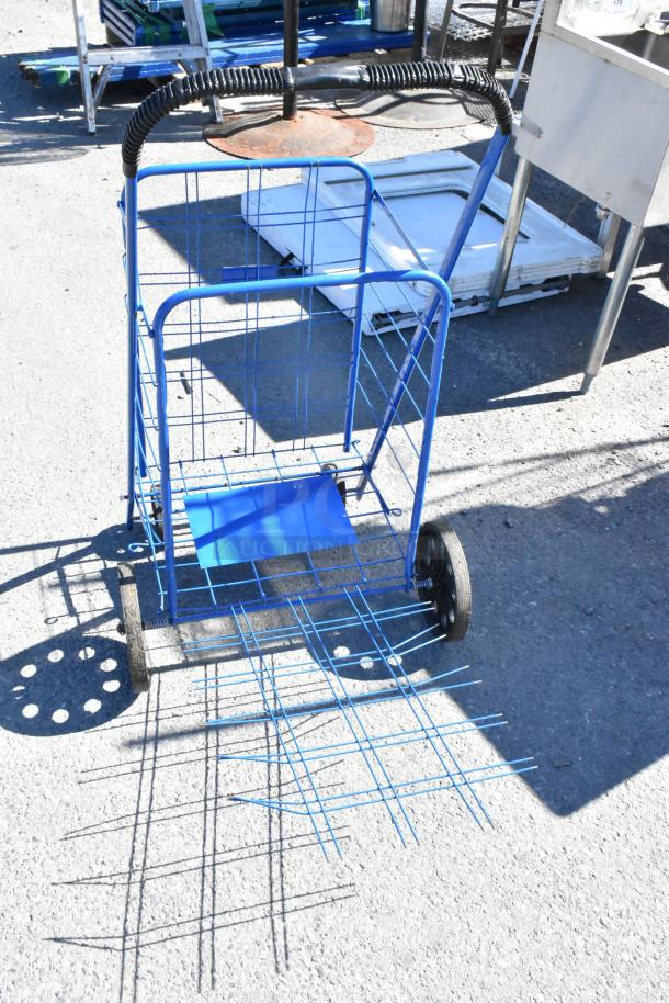 Blue wire basket cart with wheels, folding table, metal sign, and saw horse. Weathered outdoor condition.
