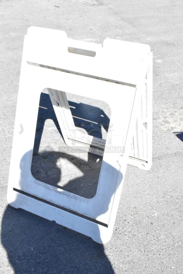 Foldable white sign on pavement, moderate wear, suitable for outdoor or indoor use, part of a mixed auction lot.