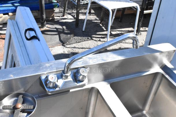 Stainless steel 3-bay sink with glass washer, featuring dual faucets. Used condition with slight wear visible.
