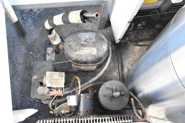 Tecumseh compressor unit with visible wiring and exterior wear. Metal casing and labels showing model information.