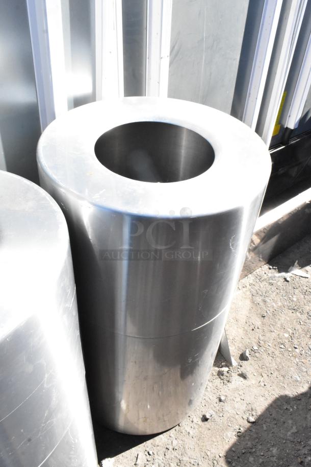 Two metal trash can shells, silver finish, cylindrical shape, used condition, suitable for outdoor or industrial use.