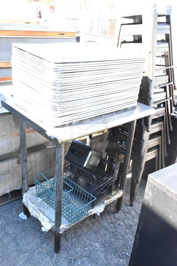 Stainless steel table with stack of full-size baking pans. Lower shelf holds containers and miscellaneous items. Used condition.