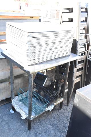 Stainless steel table with stack of full-size baking pans. Lower shelf holds containers and miscellaneous items. Used condition.