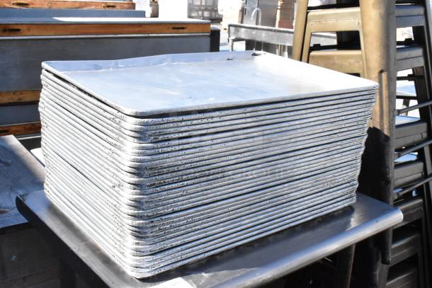 Stainless steel table with stack of full-size baking pans, showing slight wear, suitable for commercial kitchens.