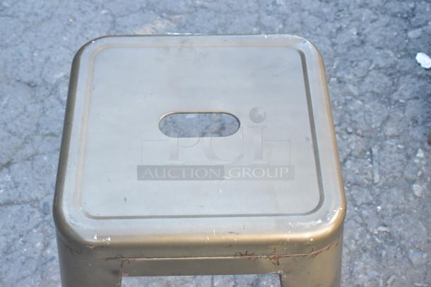 9 metal Tolix style bar height stools, metallic finish, featuring a cutout handle on the seat. Used condition with slight wear.