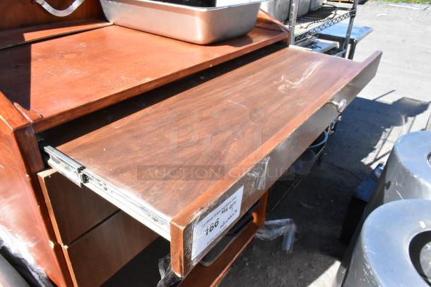 Wood pattern stand with two sliding drawers, metal handles; visible wear on surface. Label indicates auction item details.