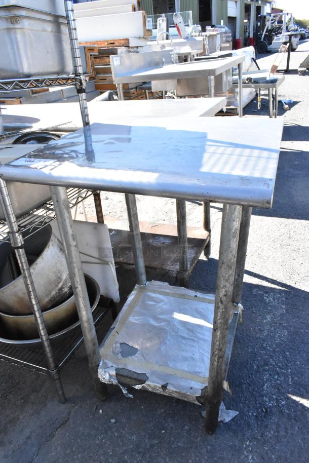 Stainless steel table with metal under shelf, shows signs of wear. Ideal for industrial or kitchen use.