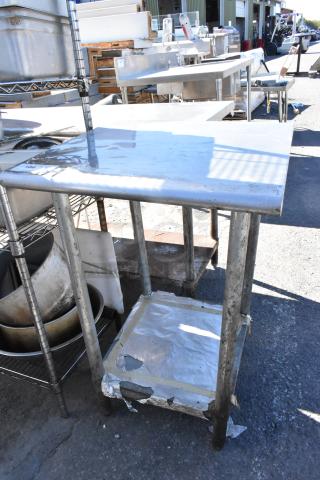 Stainless steel table with metal under shelf, shows signs of wear. Ideal for industrial or kitchen use.