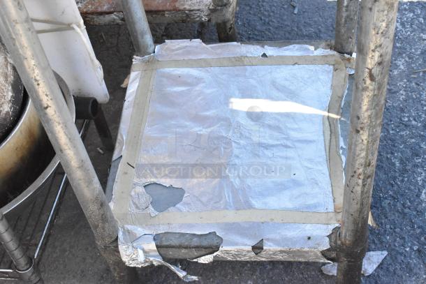 Stainless steel table with metal under shelf, worn condition, visible wear on edges, suitable for industrial use.