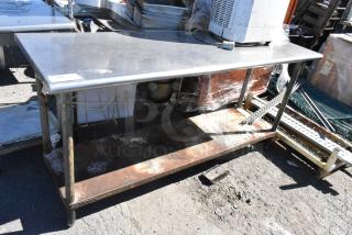 Stainless steel table with metal under shelf; surface shows some wear and rust. Ideal for industrial or kitchen use.